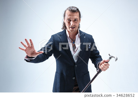 The mature barded man in a suit holding cane. 34628652