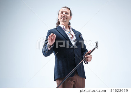 The mature barded man in a suit holding cane. The mature barded man in a suit holding cane. 34628659