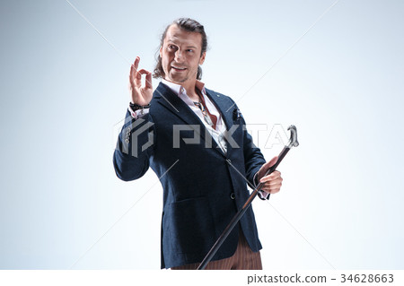The mature barded man in a suit holding cane. 34628663