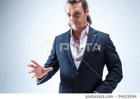 The mature barded man in a suit holding cane. 34628694