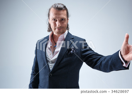The mature barded man in a suit holding cane. 34628697