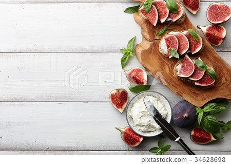Fresh figs, basil and cream cheese bruschetta on white table 34628698