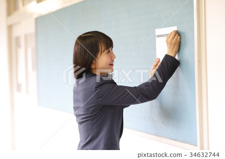 Teacher putting print on bulletin board 34632744