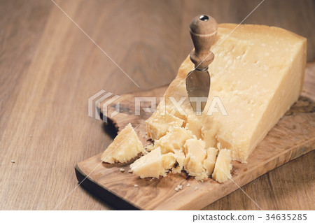 pieces of hard parmesan cheese on olive board from 34635285