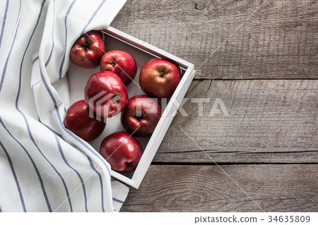 Ripe red apples in birch-box on wooden board. 34635809