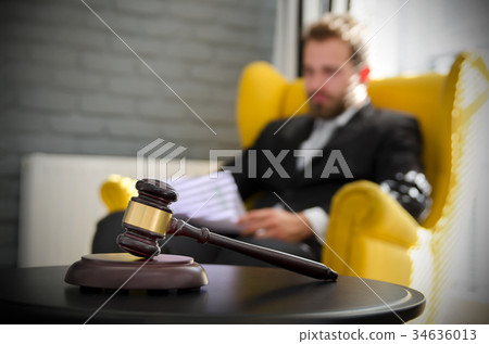 Wooden gavel, working lawyer in background Wooden gavel, working lawyer in background 34636013