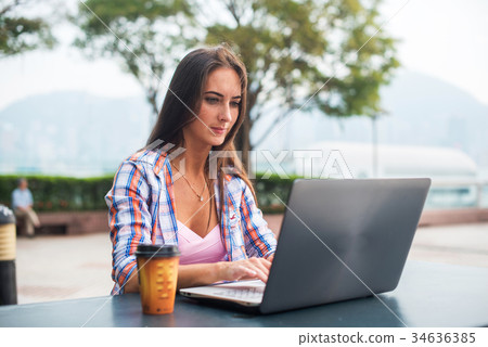 Young woman typing on a laptop studying or working Young woman typing on a laptop studying or working 34636385