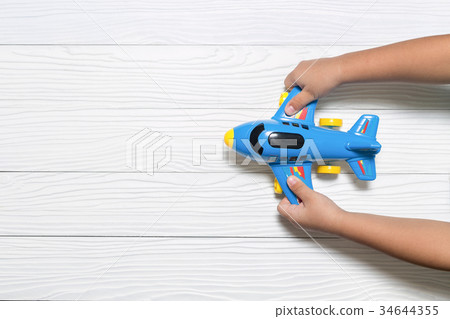Little kid holding blue airplane toy. 34644355