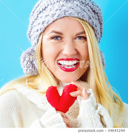 Happy young woman holding a heart cushion 34645294
