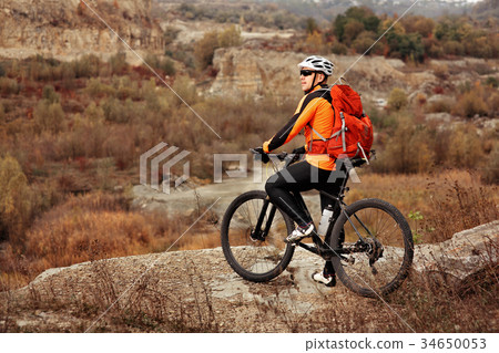 back view of a man with a bicycle and red backpack 34650053