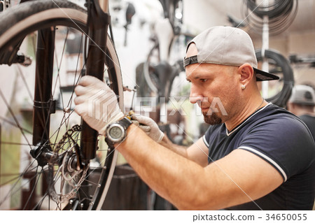 Mechanic repairing a mountain bike in a workshop 34650055