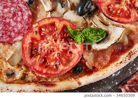 Closeup of pizza with salami, tomatoes and olives Closeup of pizza with salami, tomatoes and olives 34650309