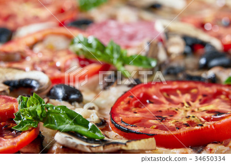 Closeup of pizza with salami, tomatoes and olives Closeup of pizza with salami, tomatoes and olives 34650334