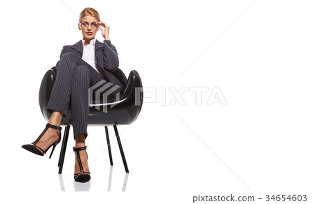 Blonde business woman sitting  black chair isolated on white 34654603