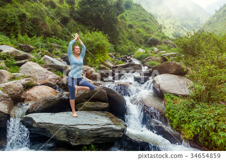 Woman in yoga asana Vrikshasana tree pose at 34654859