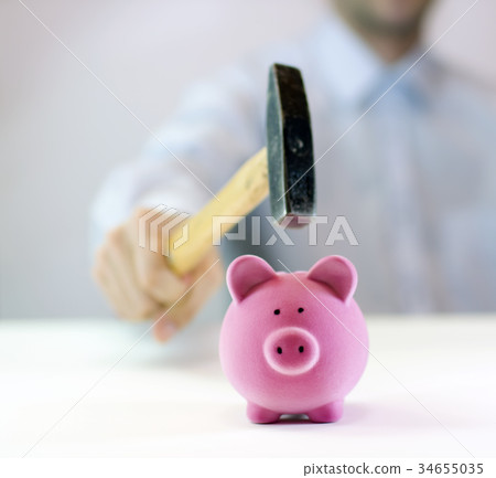 Pink piggy bank and hand with hammer Pink piggy bank and hand with hammer 34655035