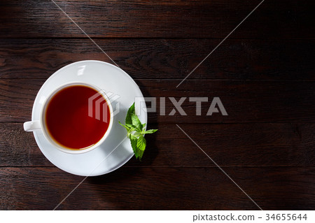 Cup with tea and teapot on wooden background Cup with tea and teapot on wooden background 34655644