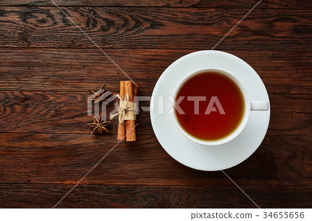 A cup of tea on a rustic wooden board, top view A cup of tea on a rustic wooden board, top view 34655656