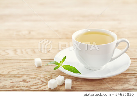 Cup with tea and teapot on wooden background 34655830