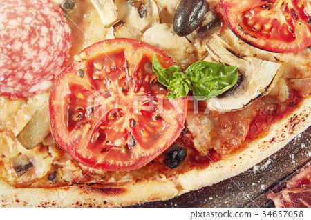Closeup of pizza with salami, tomatoes and olives Closeup of pizza with salami, tomatoes and olives 34657058