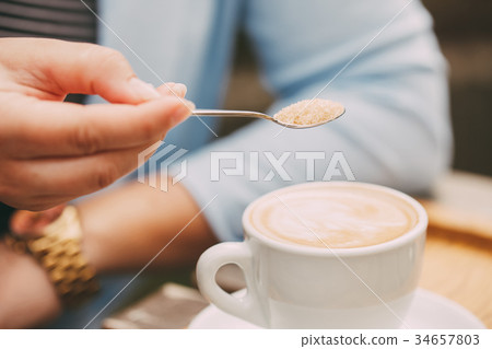 Spoon in a female hand pouring sugar 34657803