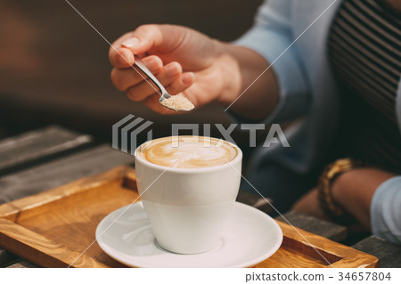 Spoon in a female hand pouring sugar 34657804