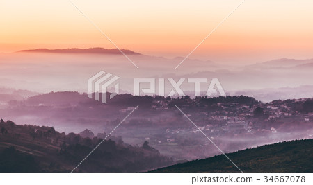 Sunset sky above layers of foggy mountains 34667078