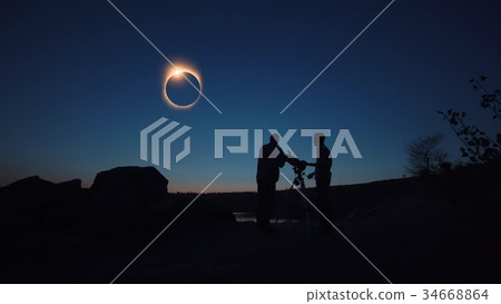 People on shore looking through telescope 34668864