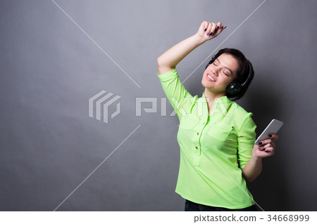 Woman with closed eyes enjoying music in earphones 34668999