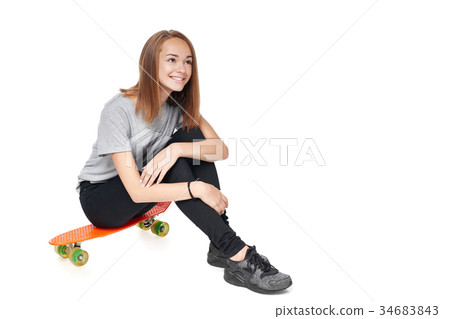Teen girl in full length sitting on skate board 34683843
