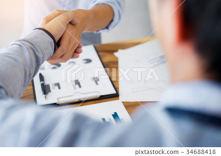 Two confident business man shaking hands during a meeting in the Two confident business man shaking hands during a meeting in the 34688418