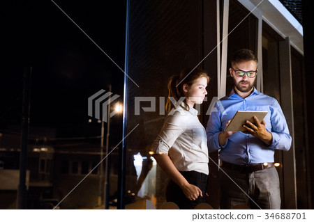 Businesspeople in the office at night working late Businesspeople in the office at night working late 34688701