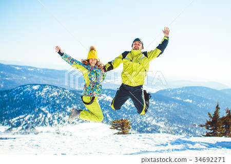 Couple jumping in the winter in the mountains Couple jumping in the winter in the mountains 34692271