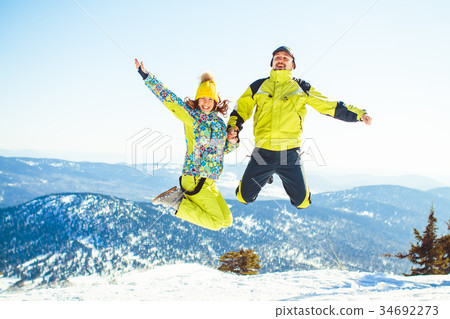 Couple jumping in the winter in the mountains Couple jumping in the winter in the mountains 34692273