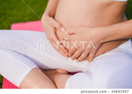 Pregnant woman with hands over tummy. 34693407