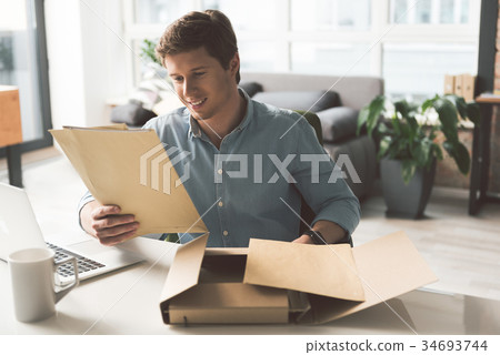 Positive young male is laboring in cozy office Positive young male is laboring in cozy office 34693744