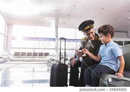 Glad aviator with son in airport Glad aviator with son in airport 34694091