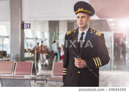 Thoughtful airman holding cup of coffee Thoughtful airman holding cup of coffee 34694269
