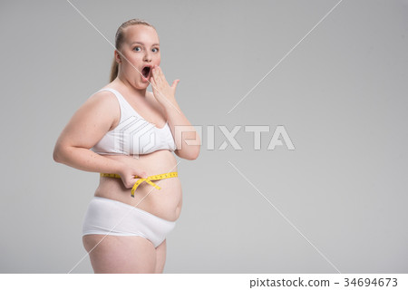 Shocked fat girl measuring her belly by tape-line 34694673