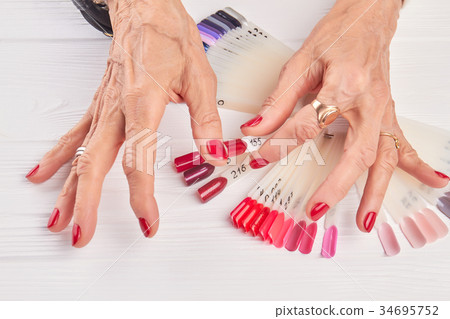 Old woman compares nail color with nail sample. 34695752