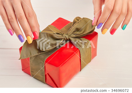 Female manicured hands and gift box. 34696072