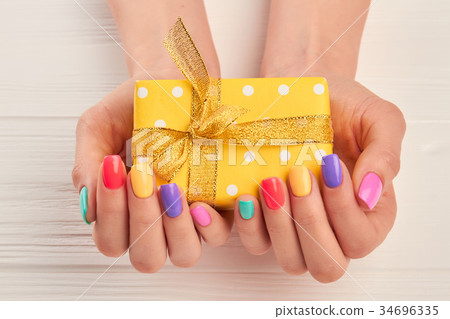 Little gift box in female manicured hands. Little gift box in female manicured hands. 34696335