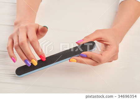 Female hands filing nails with nail file. 34696354