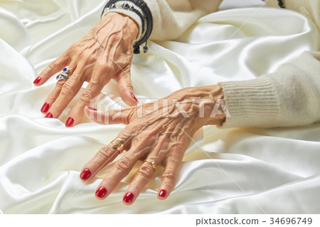 Senior manicured hands with jewelry on silk. 34696749