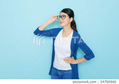 female student standing in blue wall background 34700980