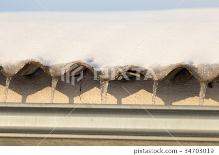Icicles on the roof of the house at sunset Icicles on the roof of the house at sunset 34703019