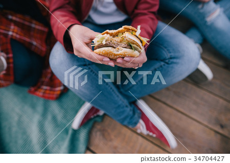 Tasty burger in woman's hands. Takeaway junk food Tasty burger in woman's hands. Takeaway junk food 34704427