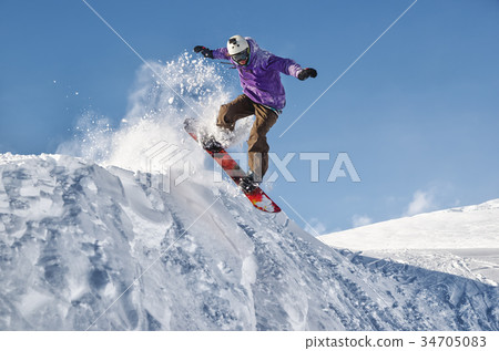 Stylish snowboarder with helmet and mask jumps Stylish snowboarder with helmet and mask jumps 34705083