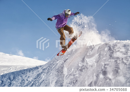 Stylish snowboarder with helmet and mask jumps 34705088
