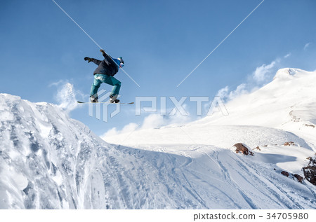 Stylish snowboarder with helmet and mask jumps 34705980